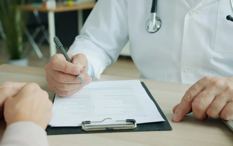 Clinician completing a patient's chart during a consultation.
