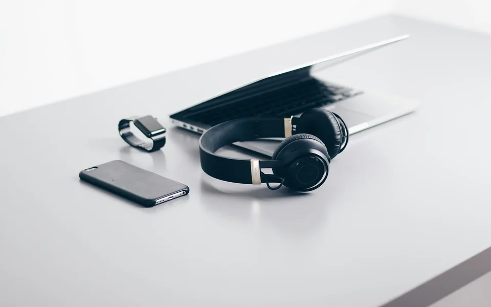 Laptop, smartphone and headphones arranged on a desk.