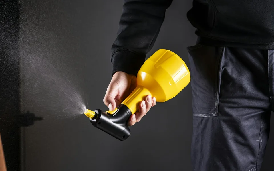 Person holding a yellow hand-held pressure sprayer.