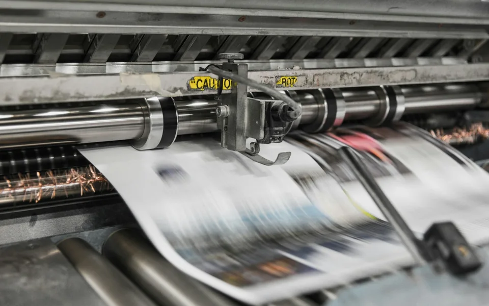 Paper moving through an industrial printing press.