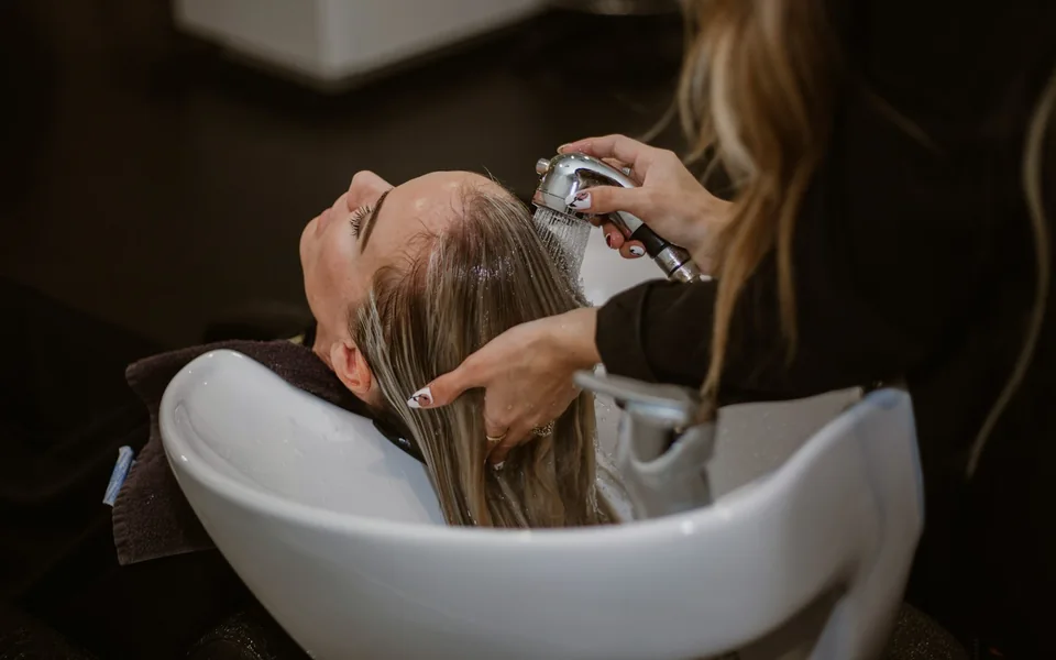 Hair stylist washing a client's hair in a salon.
